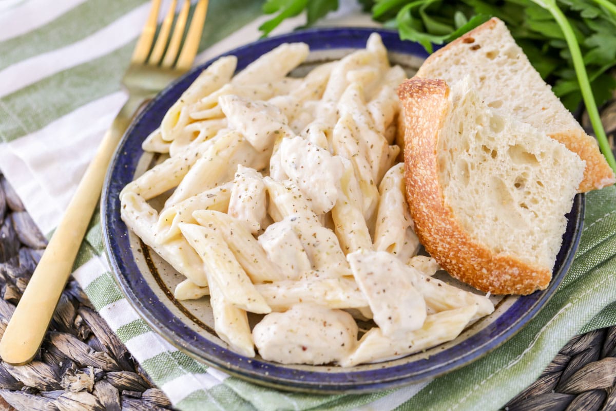 Easy chicken penne pasta served on a blue plate with two slices of bread.