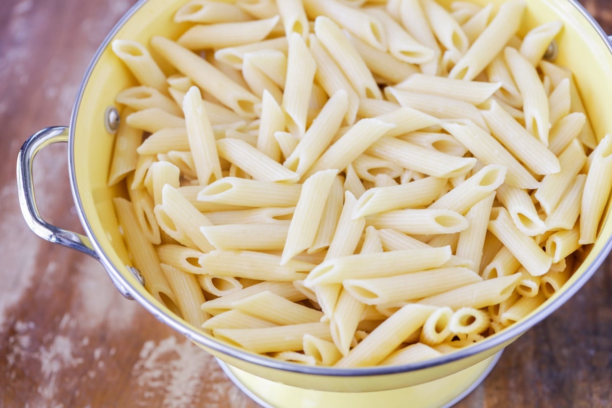Cooked Penne pasta in a yellow bowl.