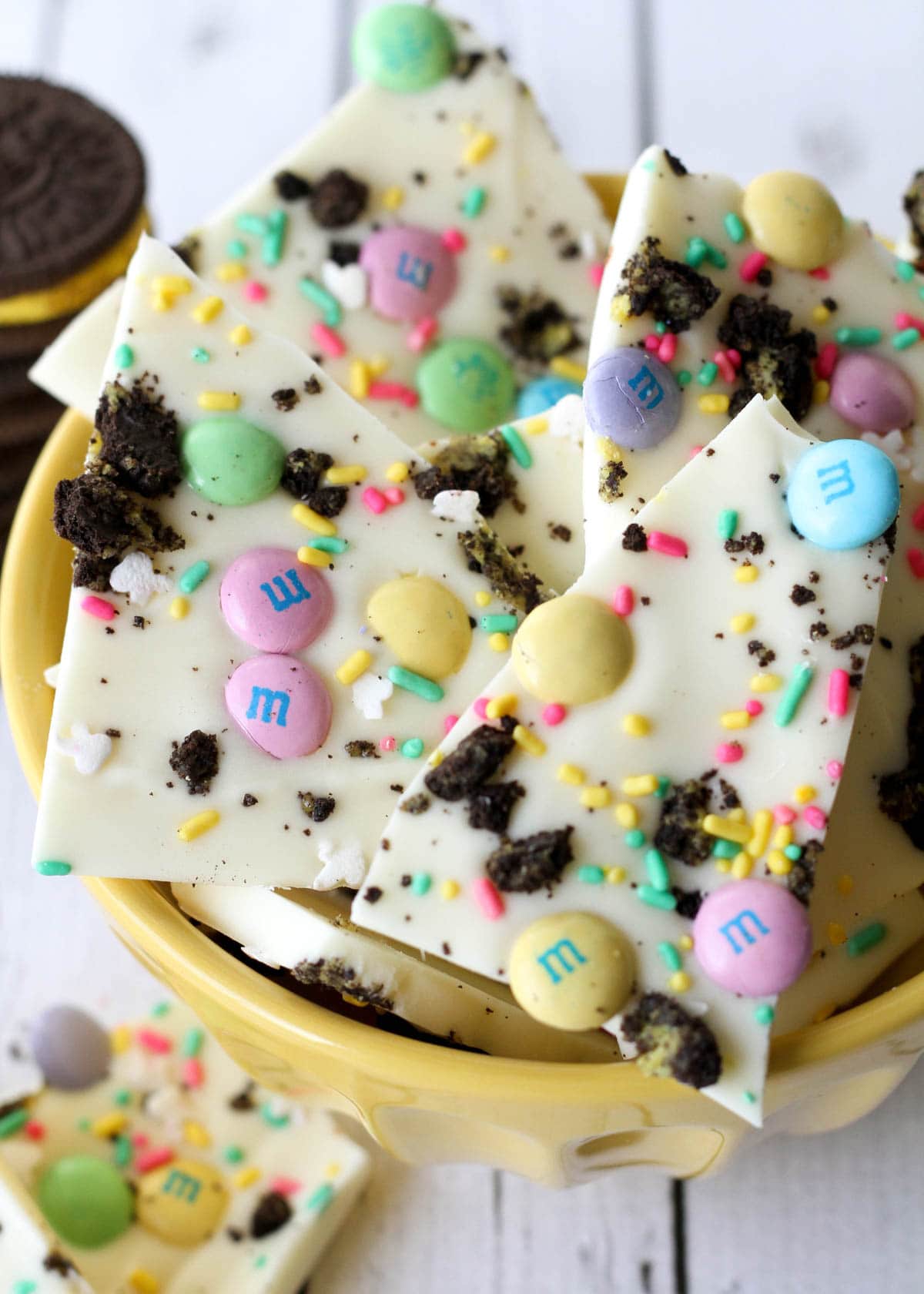 Broken up pieces of Oreo bark candy in a yellow bowl