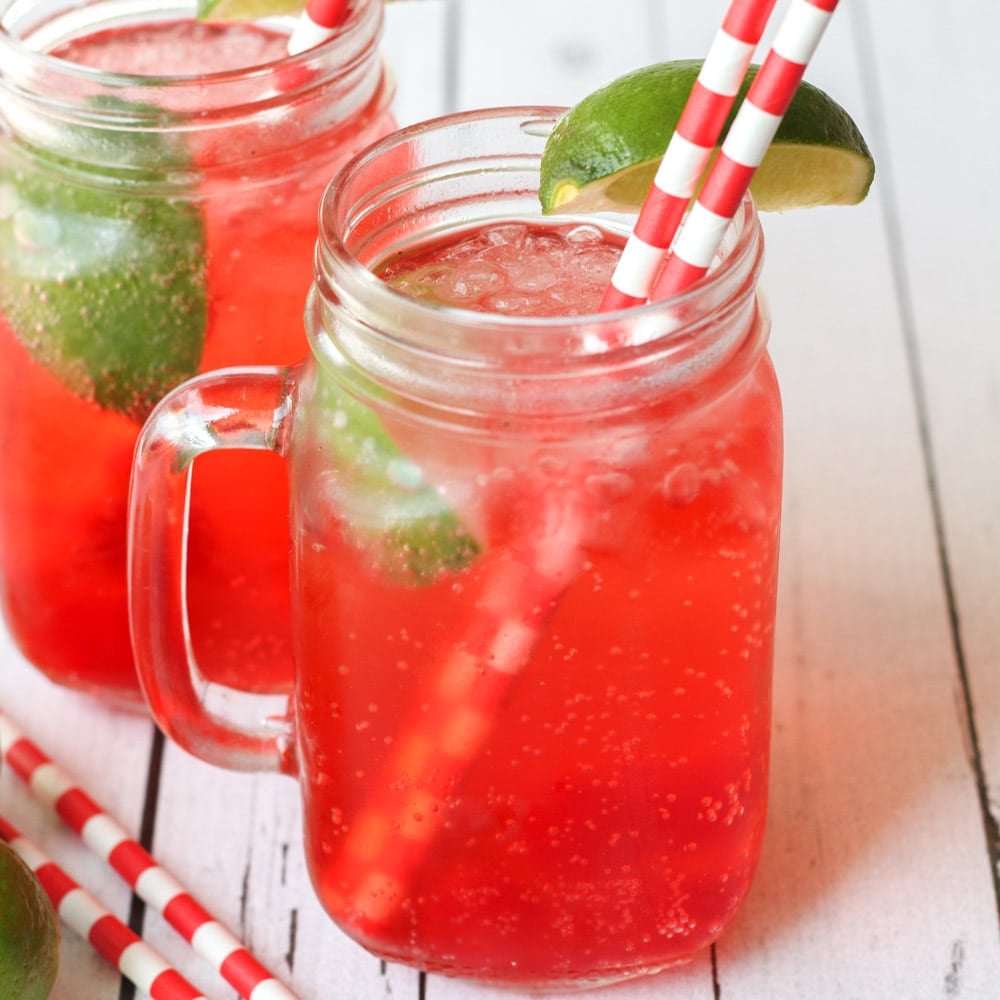 Summer Recipes - Cherry limeade in a glass mug with a straw and fresh lime.