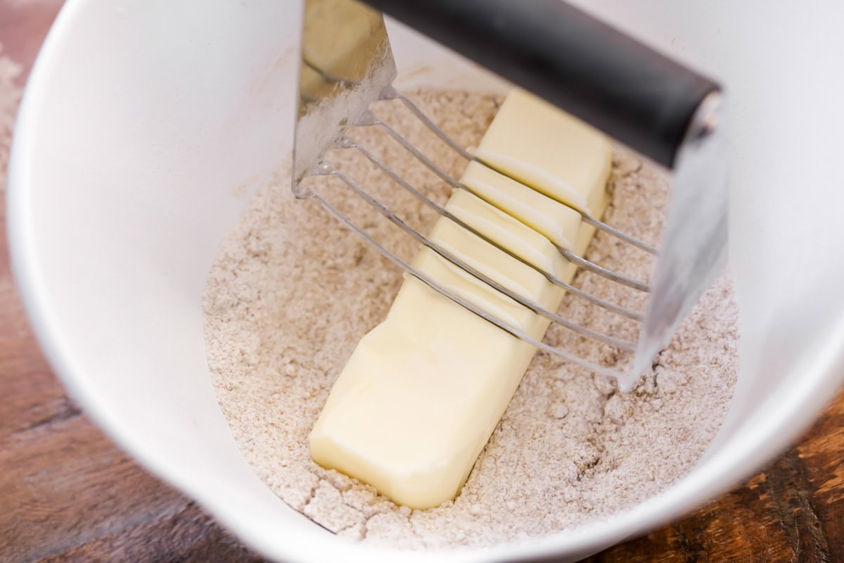 Butter being cut into flour and cinnamon mixture.