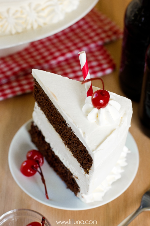 Slice of ice cream cake on a white plate topped with a cherry