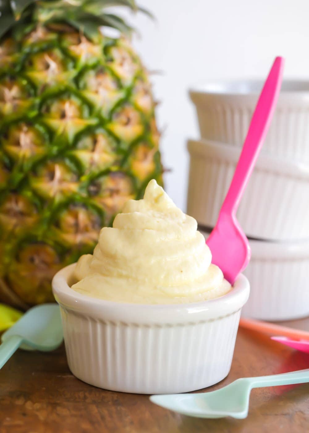 Fresh dole whip served in a white bowl with a pink spoon.