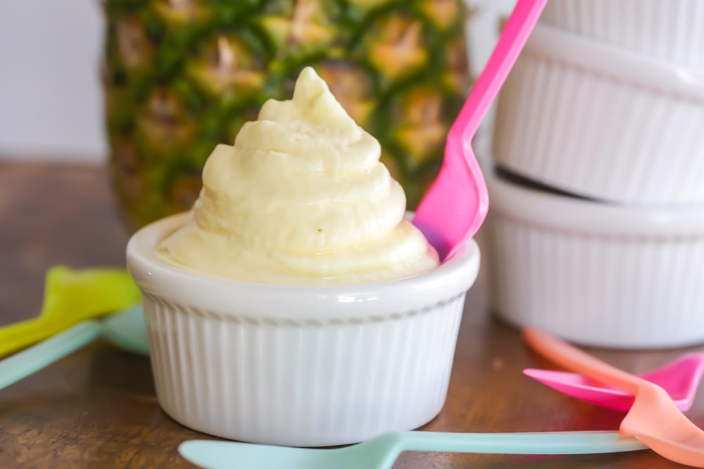 Freshly whipped dole whip served in a white bowl with a pink spoon.