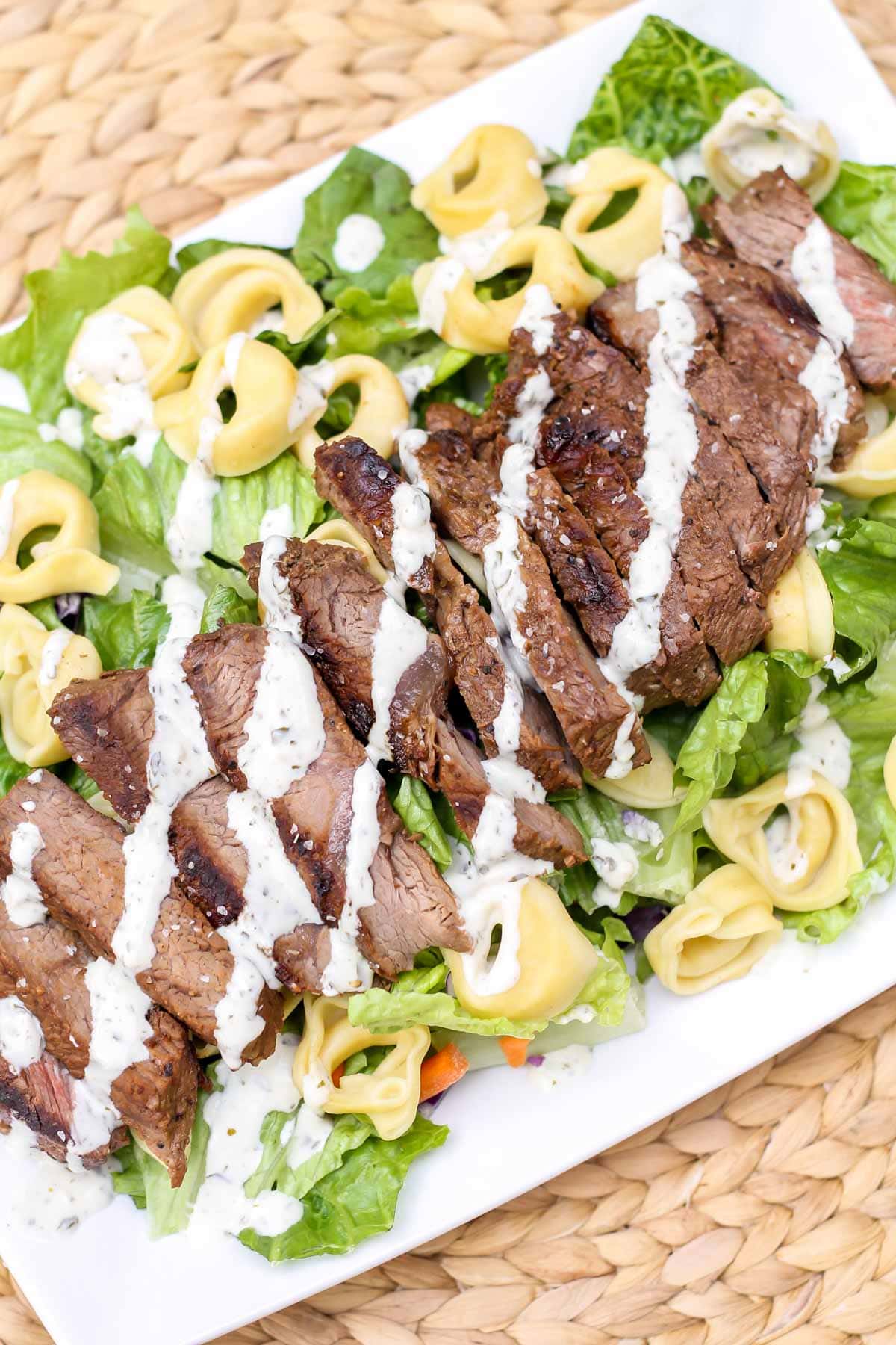 Steak and tortellini salad dressed on a white plate