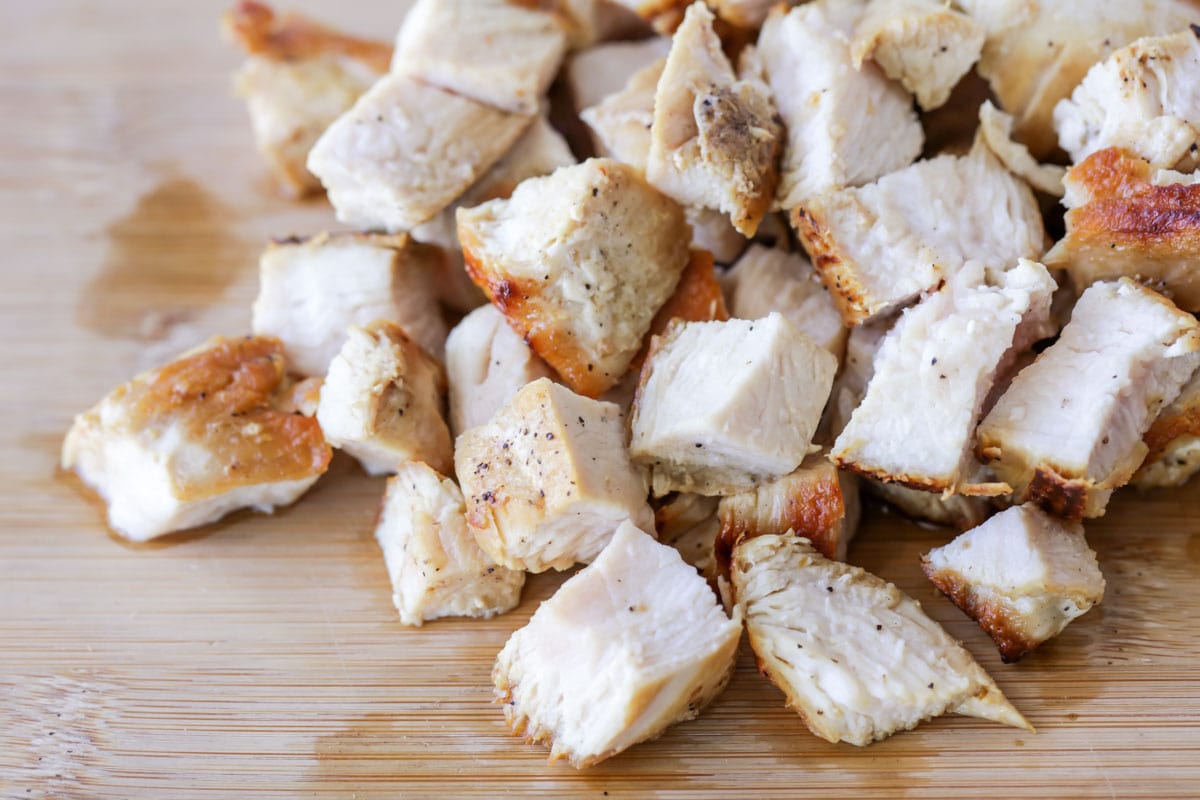 Chopped chicken on  a wooden cutting board.