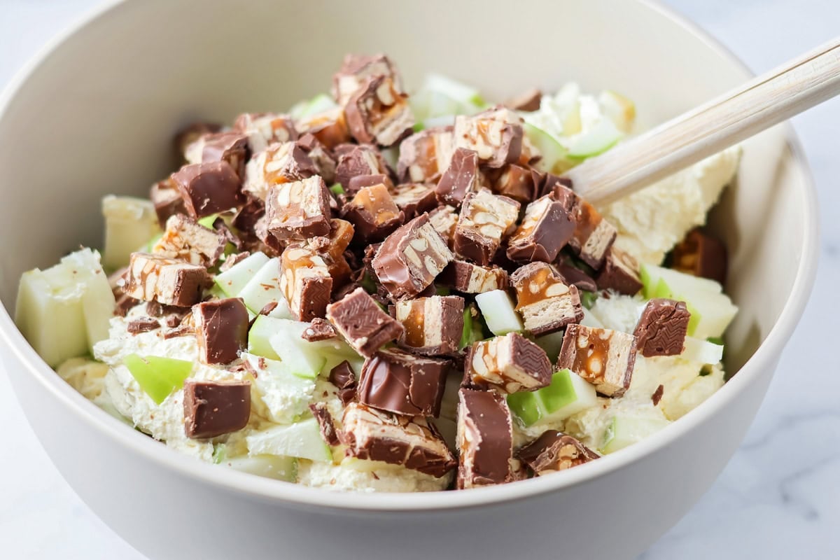 Our 10-minute Snickers salad is a sweet and tart dessert where bright pops of apples perfectly complement chewy chunks of Snickers. Adding chopped up Snickers bars and granny smith apples to cool whip and pudding mixture.
