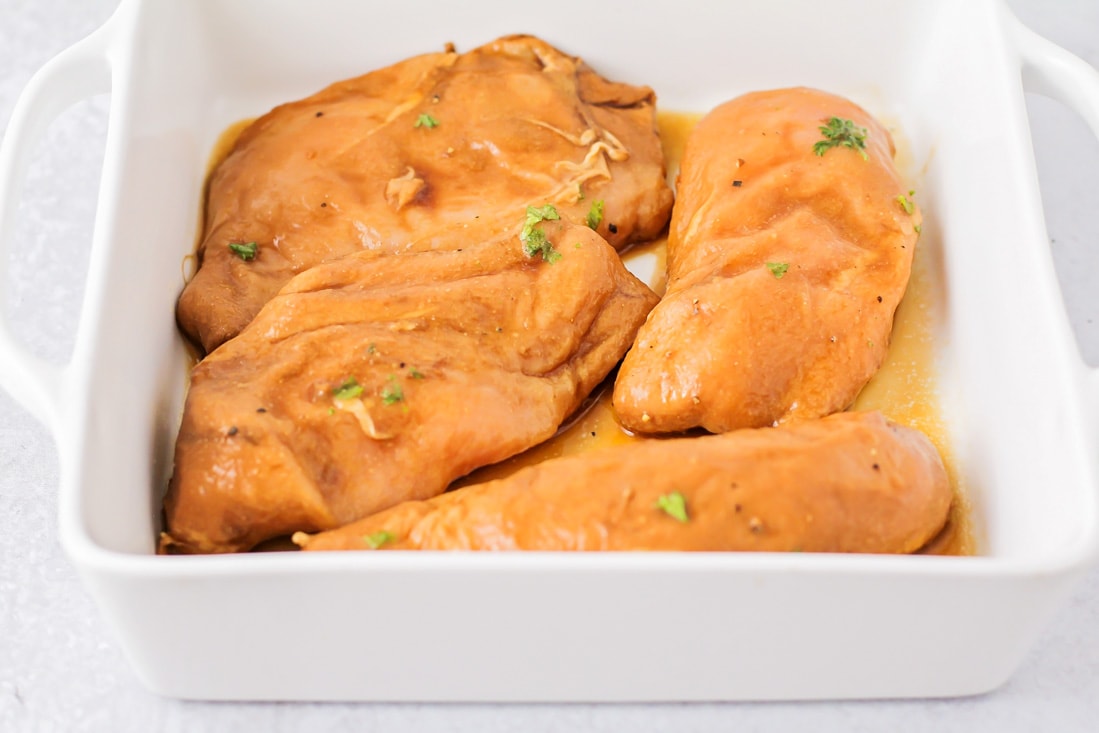 Marinated chicken breasts in a baking dish before being baked.