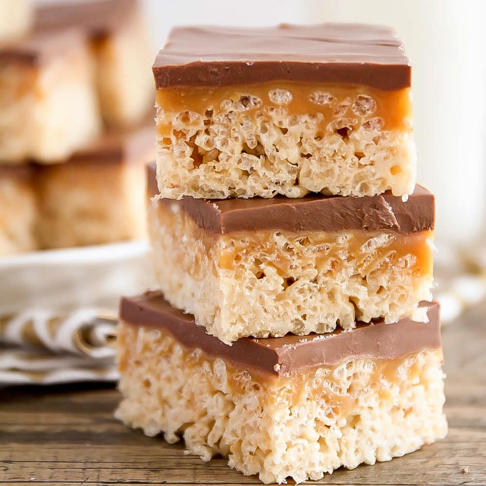 Chocolate caramel rice krispies treats stacked on a wooden table