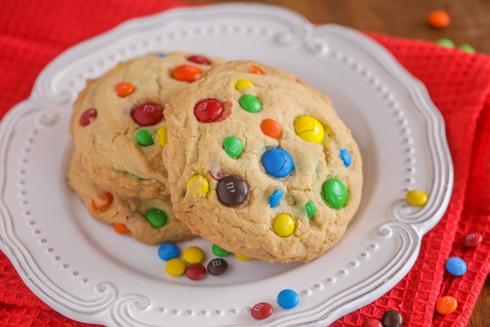 A stack of large m&m cookies on a white plate