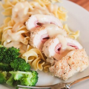 chicken cordon bleu over noodles on plate