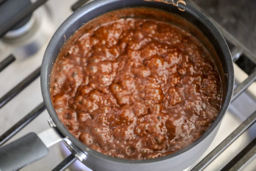 This all-time favorite hot fudge sauce recipe is a family favorite for pouring on your sweet treats. All you need is 4 ingredients! Chocolate sauce boiling in a pot on the stove.