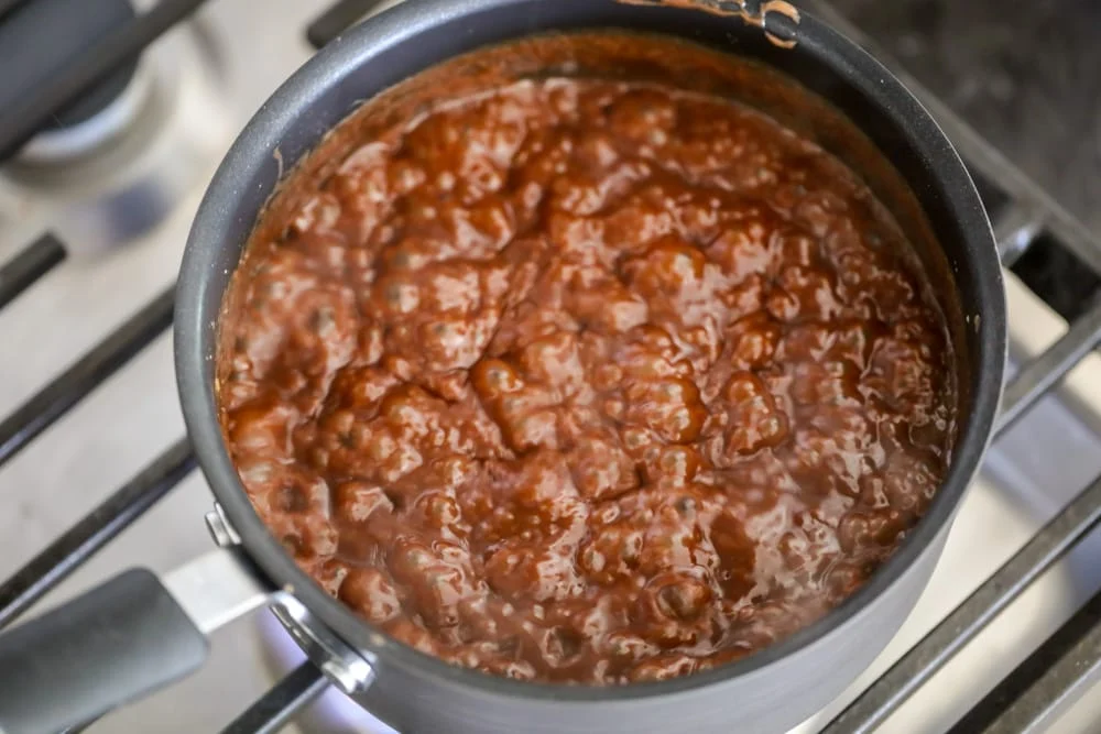 Chocolate sauce boiling in a pot on the stove.