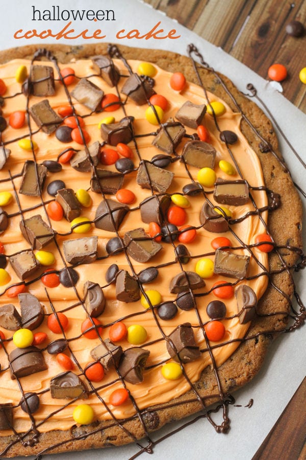 Simple and delicious Halloween Cookie Cake recipe on { lilluna.com } Super easy! A refrigerated cookie dough baked, then topped with orange frosting, reeses pieces, rolos, and chocolate syrup. 