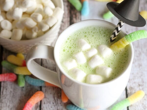 Halloween hot chocolate in a cup with candy and witch straw in it.