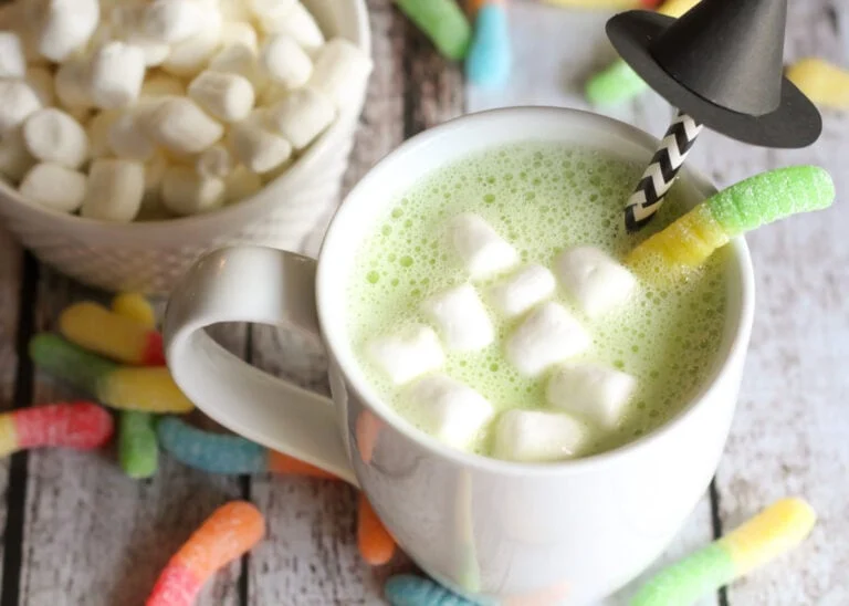 Halloween hot chocolate in a cup with candy and witch straw in it.
