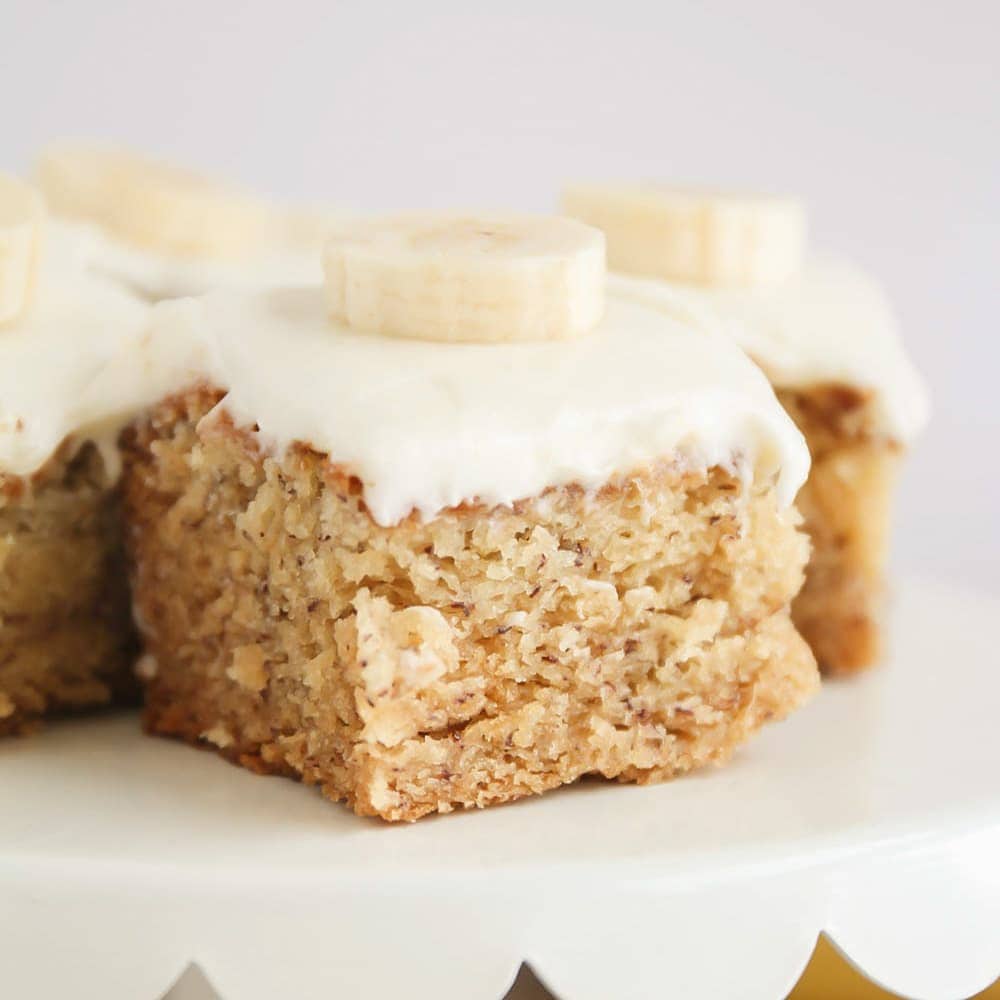 Close up of banana bar with cream cheese frosting and a banana slice on top