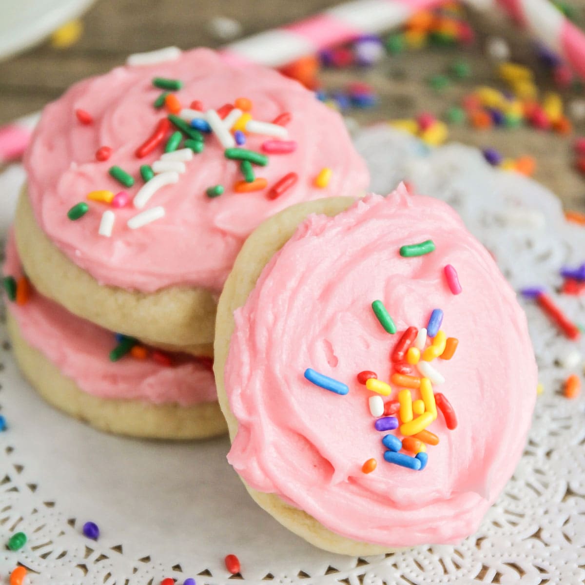 Valentine's Day Desserts - No Roll sugar cookies with pink frosting and rainbow sprinkles on a white doily. 