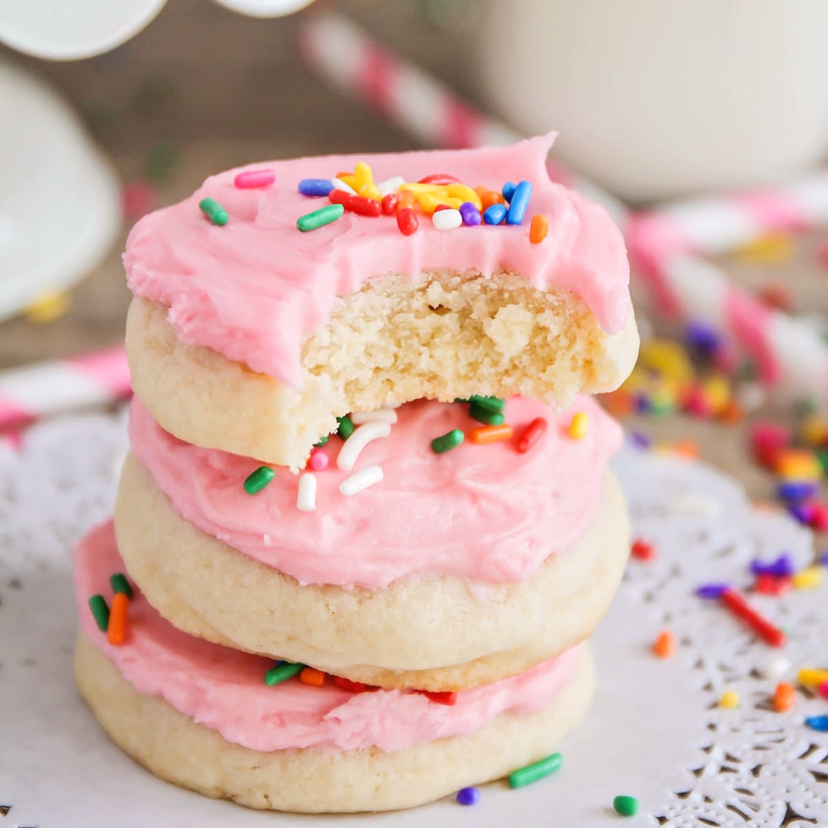 Sugar cookie recipes - no roll sugar cookies with pink frosting stacked on a plate.
