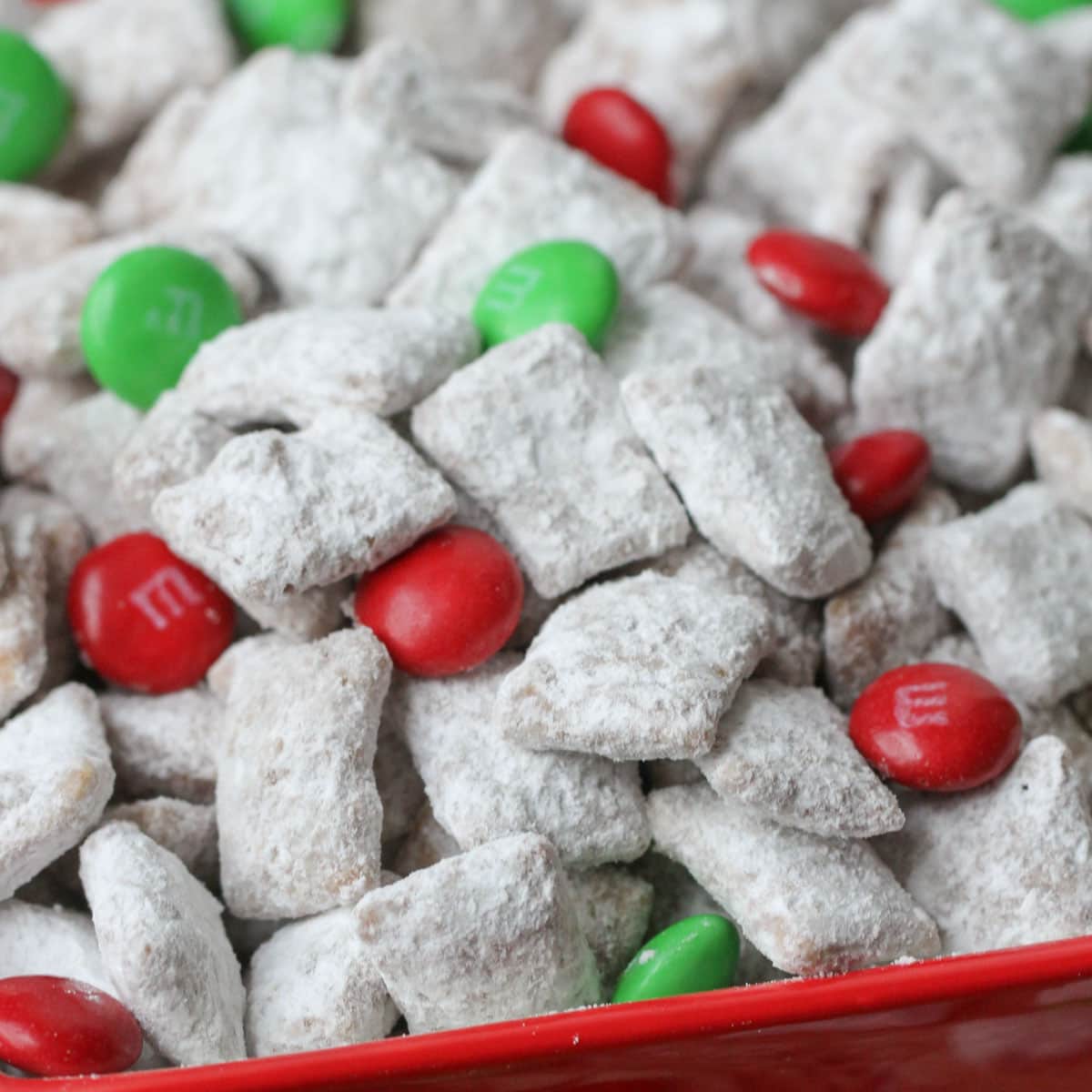 Christmas puppy chow tossed with holiday M&Ms in a red bowl