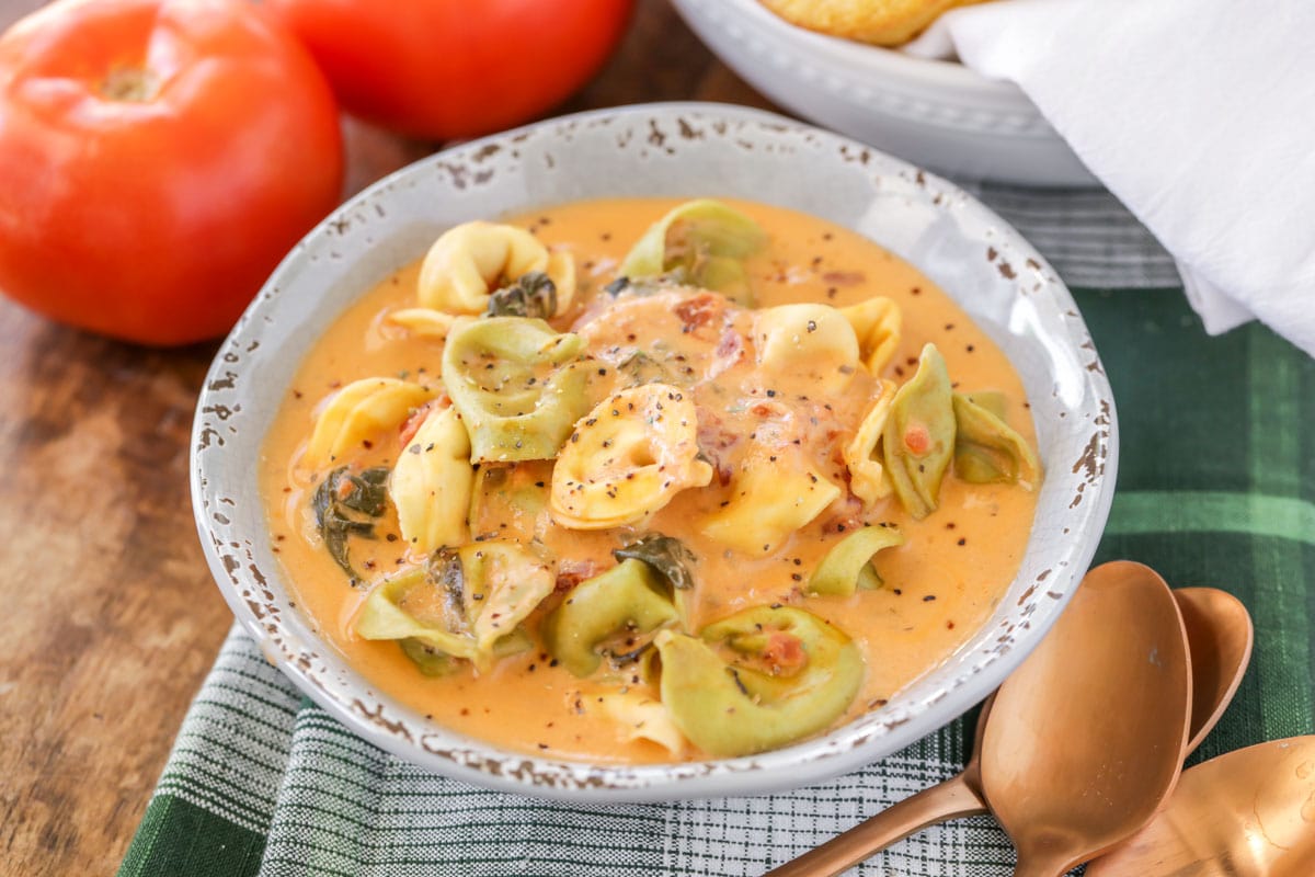 Crock pot spinach tortellini soup in a grey bowl.