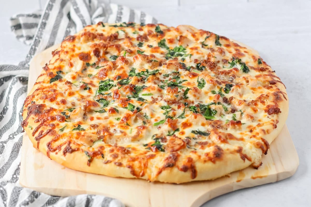 Chicken Alfredo pizza recipe on cutting board.