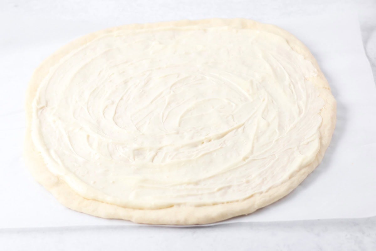Alfredo sauce spread over pizza dough.