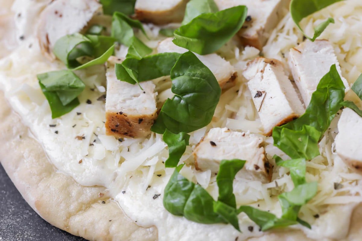 Pizza Alfredo de espinacas con todos los ingredientes antes de ser horneada