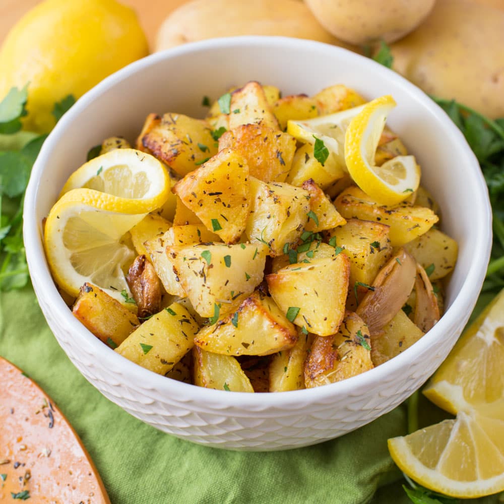 Easy side dishes - a bowl of herb roasted potatoes served with lemon slices.