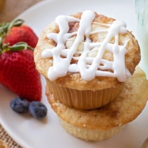 Cinnamon roll muffins topped with glaze and served with fresh berries.
