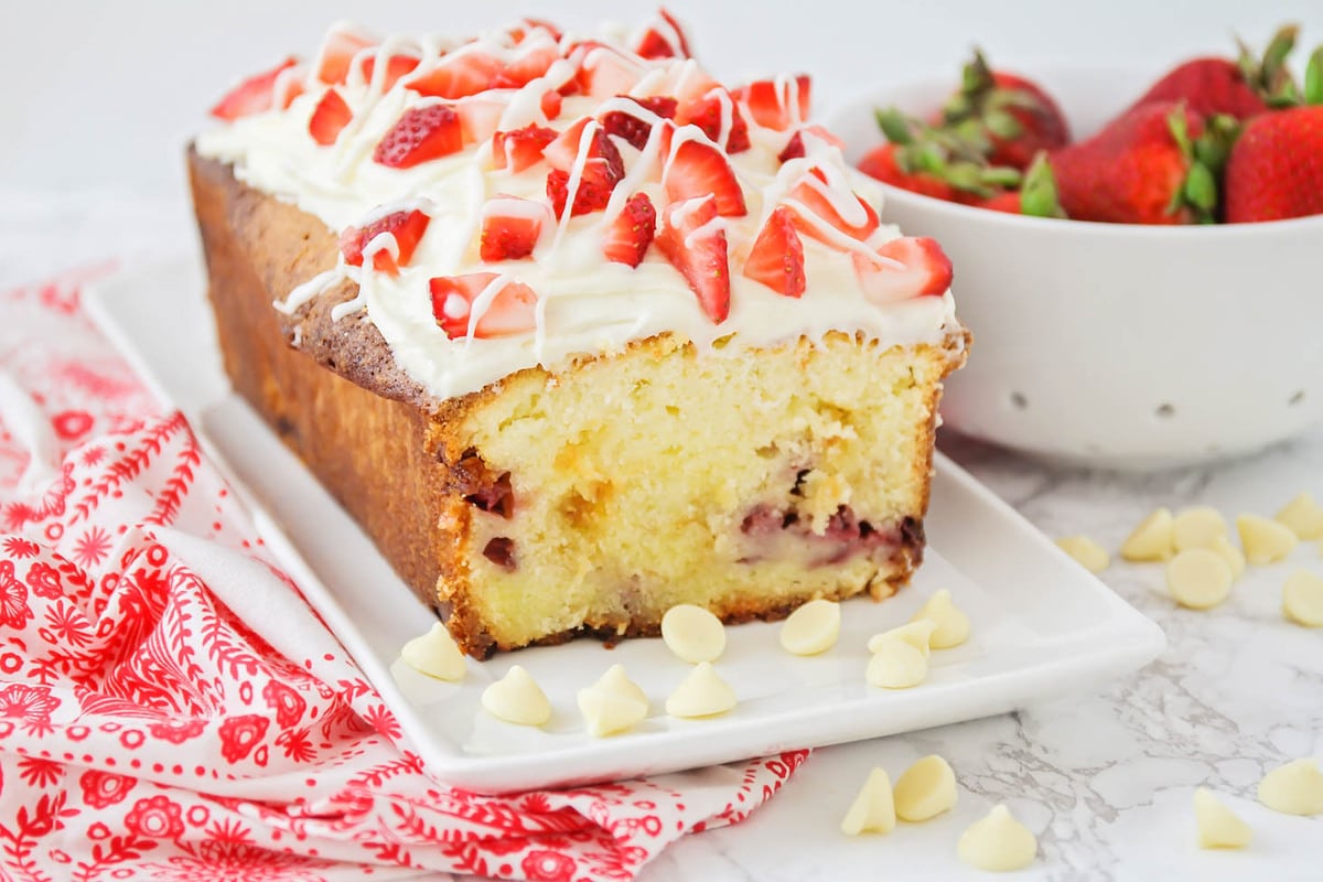 Valentine's Day Desserts - Strawberry Pound Cake topped with strawberries and drizzled white chocolate on a white platter. 