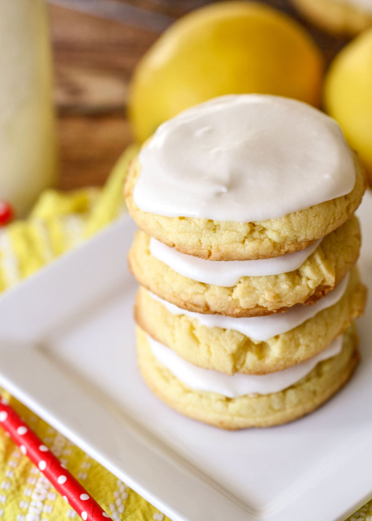 Frosted lemon cookies stacked on a white plate