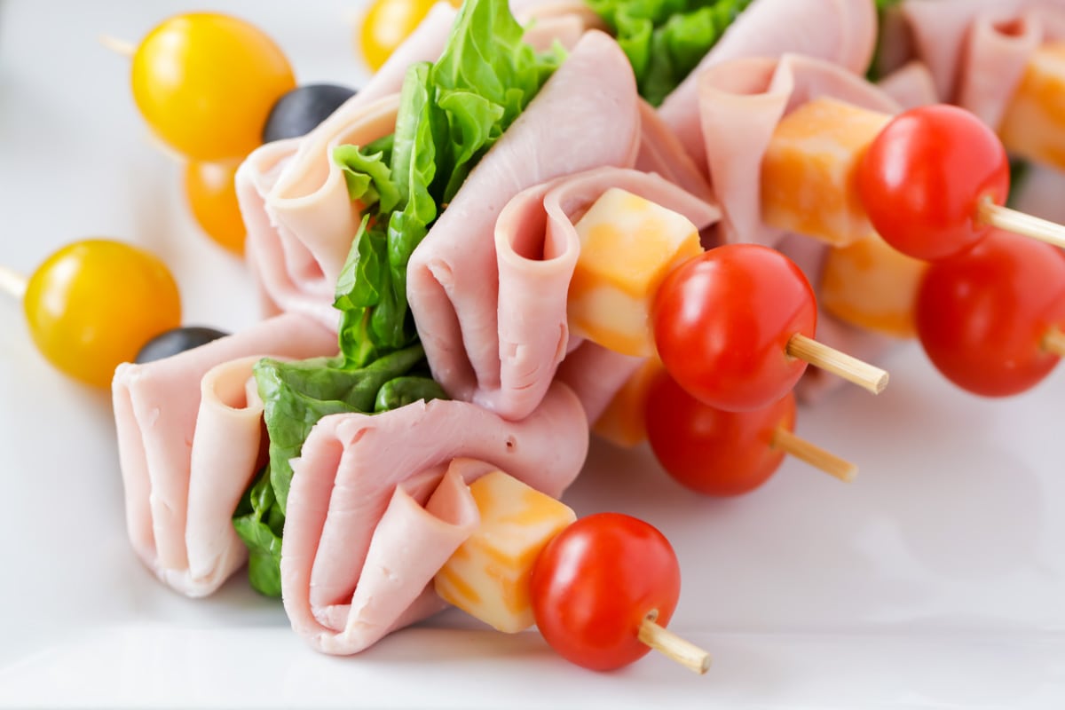 Lunch kabobs of meat cheese, tomato, and lettuce served on a white plate, a favorite dinner idea for kids.