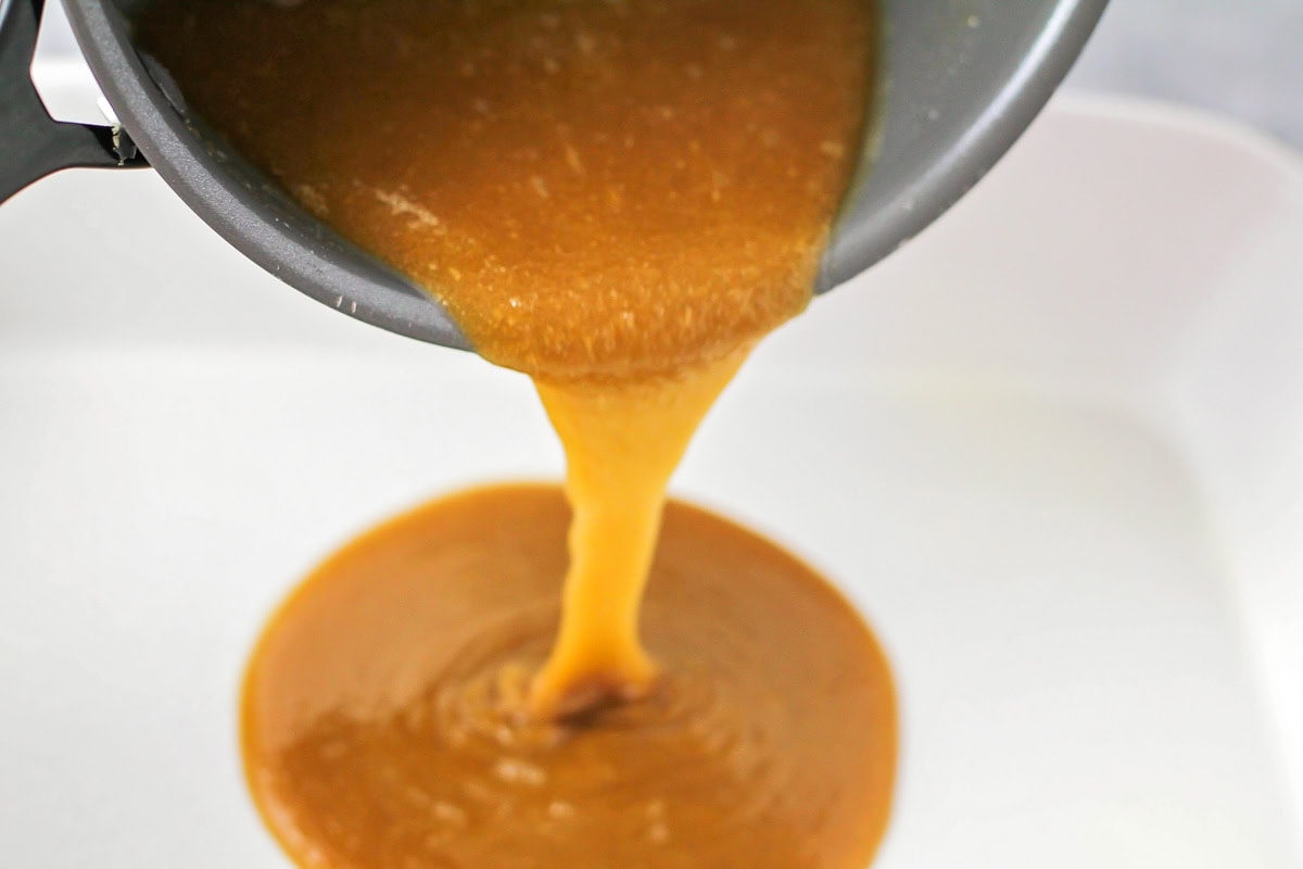 Pineapple upside down cake brown sugar sauce being poured into the bottom of the pan.