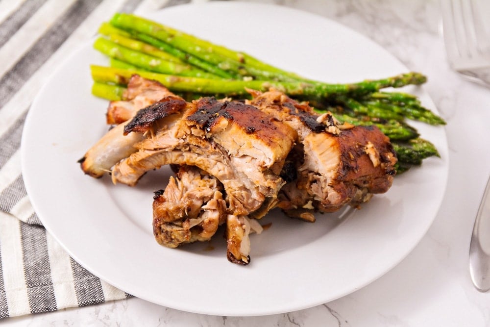 Dr. Pepper ribs cut on plate with a side of asparagus.