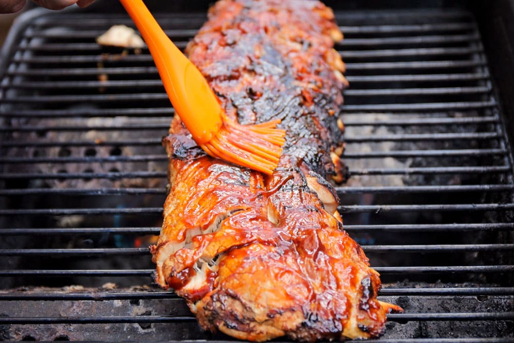 Boil and grill ribs being basted with bbq sauce.