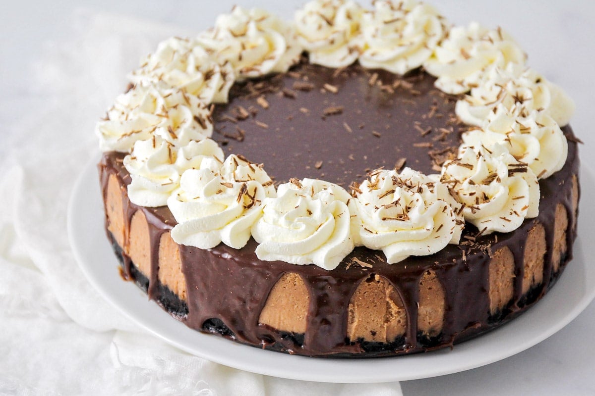 A cheesecake topped with chocolate ganache and whipped cream.