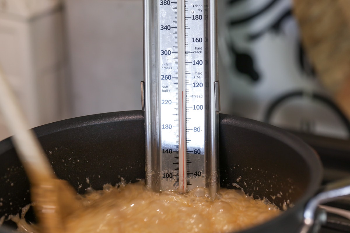 candy thermometer in a pot of cooking sugar mixture