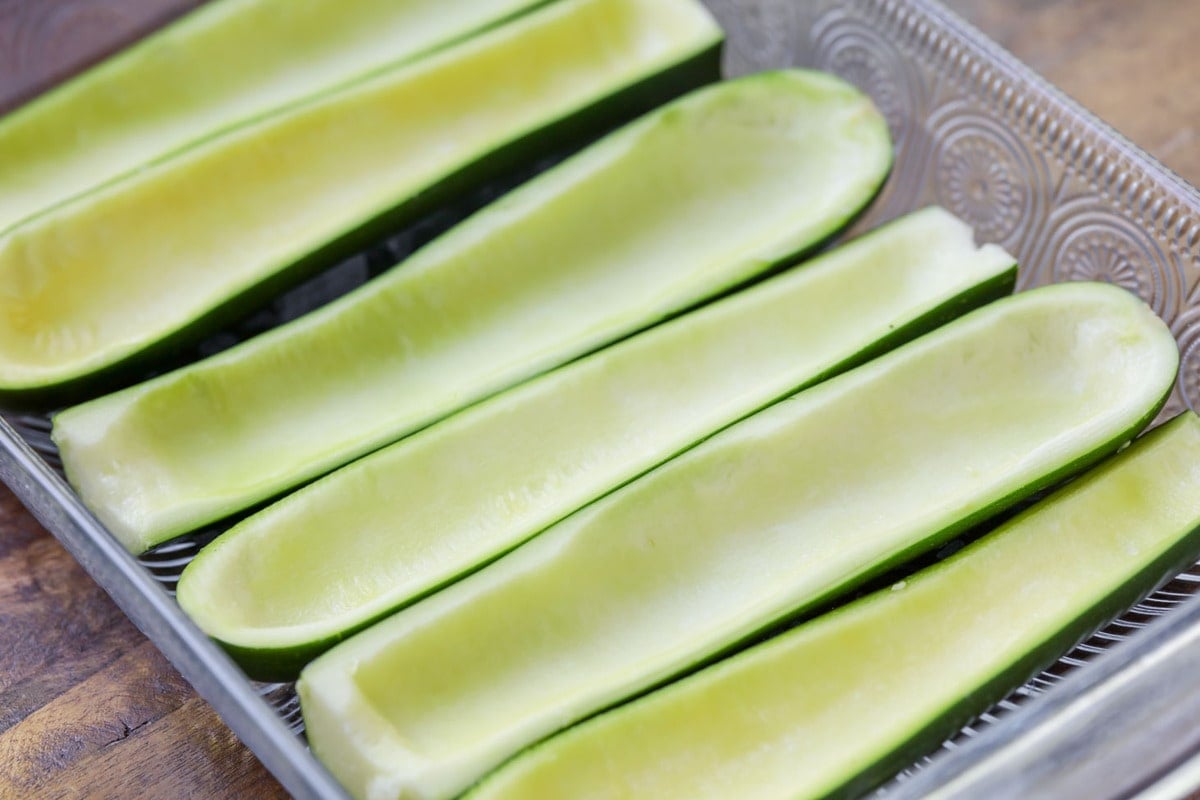 How to Make Zucchini Boats scooped out on a glass dish.