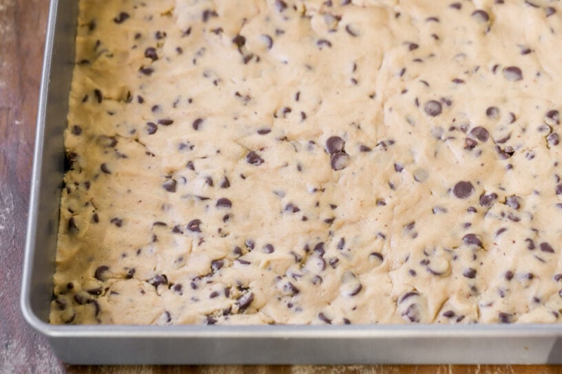 Cookie dough base pressed in a metal pan.
