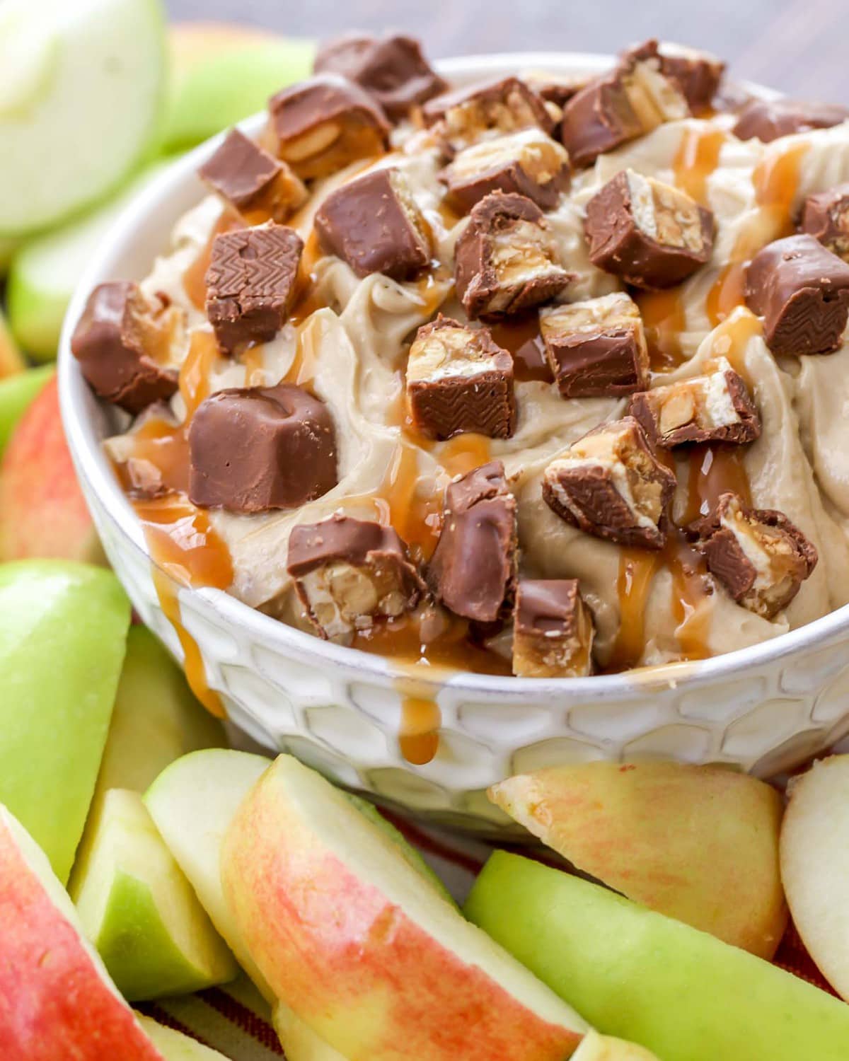 Close up of snickers topped dip in a white bowl