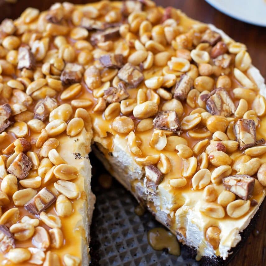 No bake Snickers cheesecake close up image with slice cut out.
