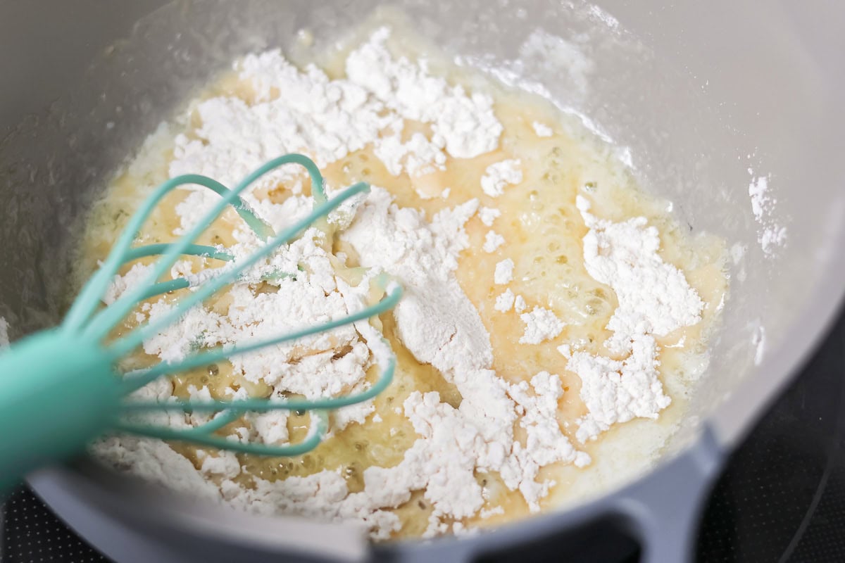 Adding flour to the butter mixture to make a roux for ham and potato soup.