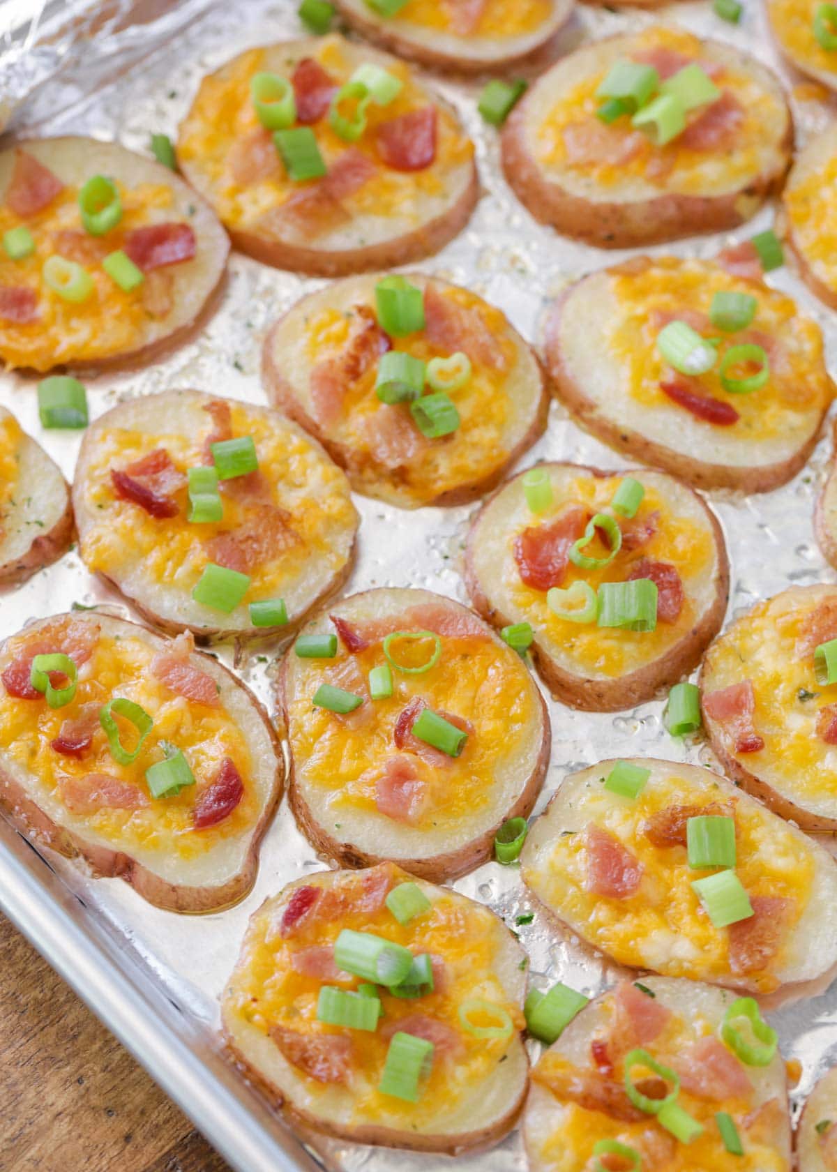 Loaded baked potato rounds on a pan topped with green onions
