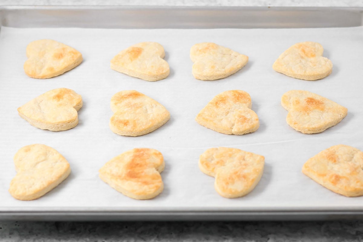 Baked pie crust hearts on baking sheet.