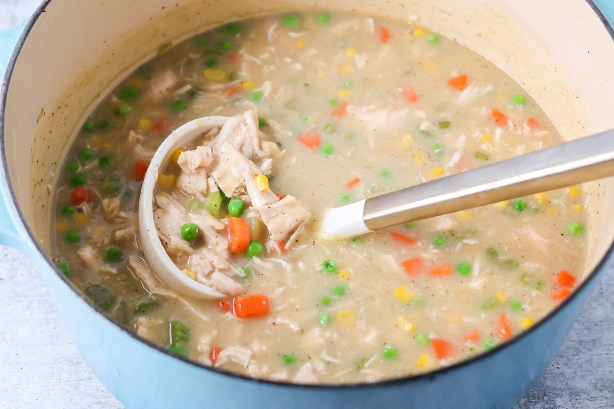 Chicken pot pie soup being served from pot.