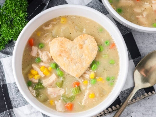Chicken pot pie soup served in bowl with pie crust heart on top.