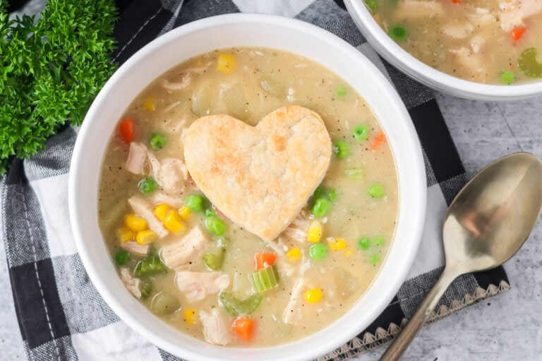 Chicken pot pie soup served in bowl with pie crust heart on top.