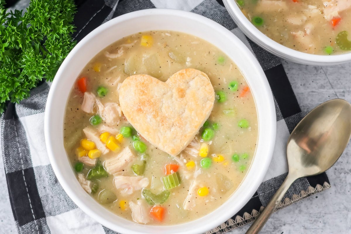 Chicken pot pie soup served in bowl with pie crust heart on top.