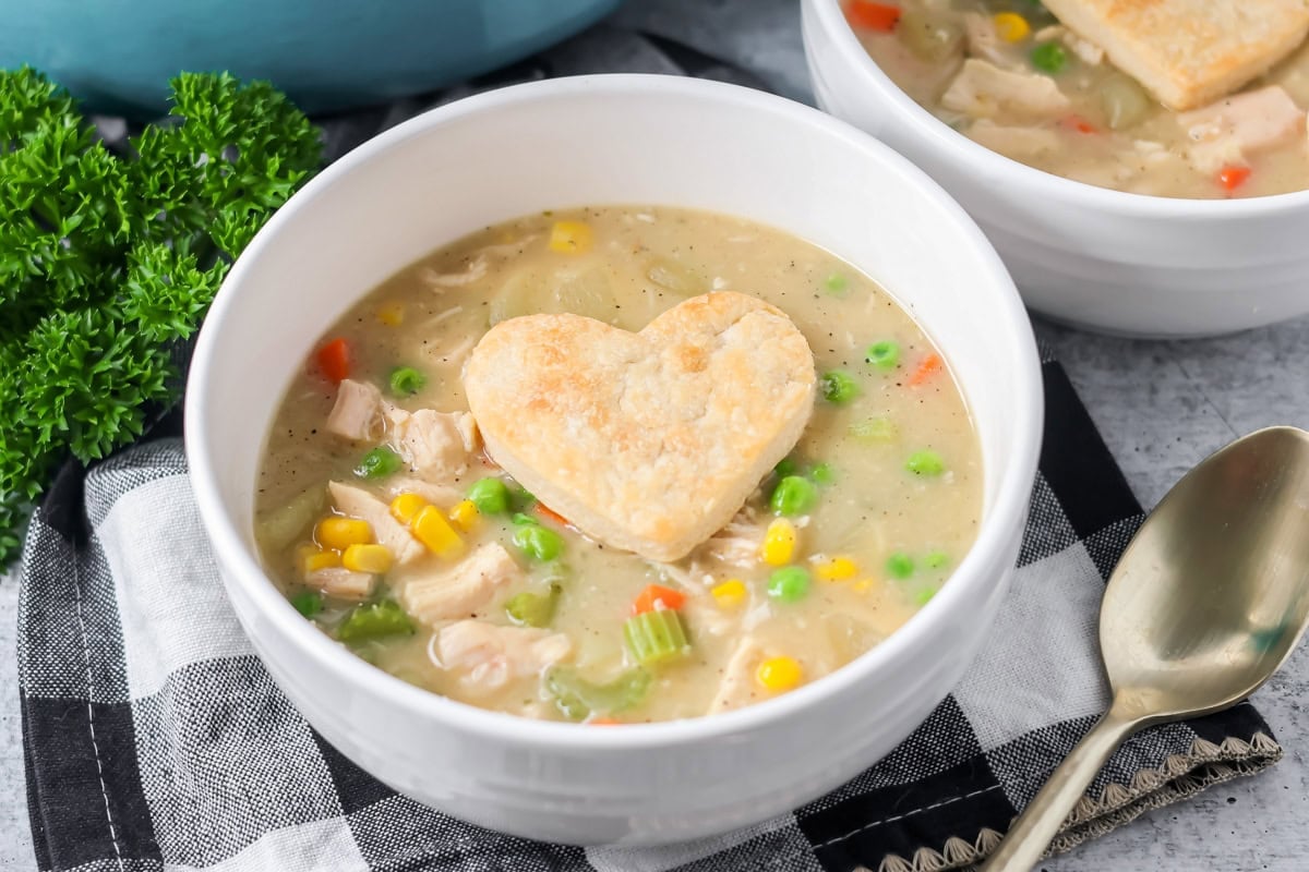 Chicken pot pie soup being served in a bowl with flaky pie crust hearts.